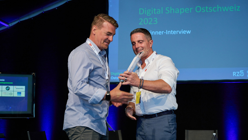 MetroComm-Chefredaktor Stephan Ziegler (rechts) übergibt Roger Spirig die Auszeichnung